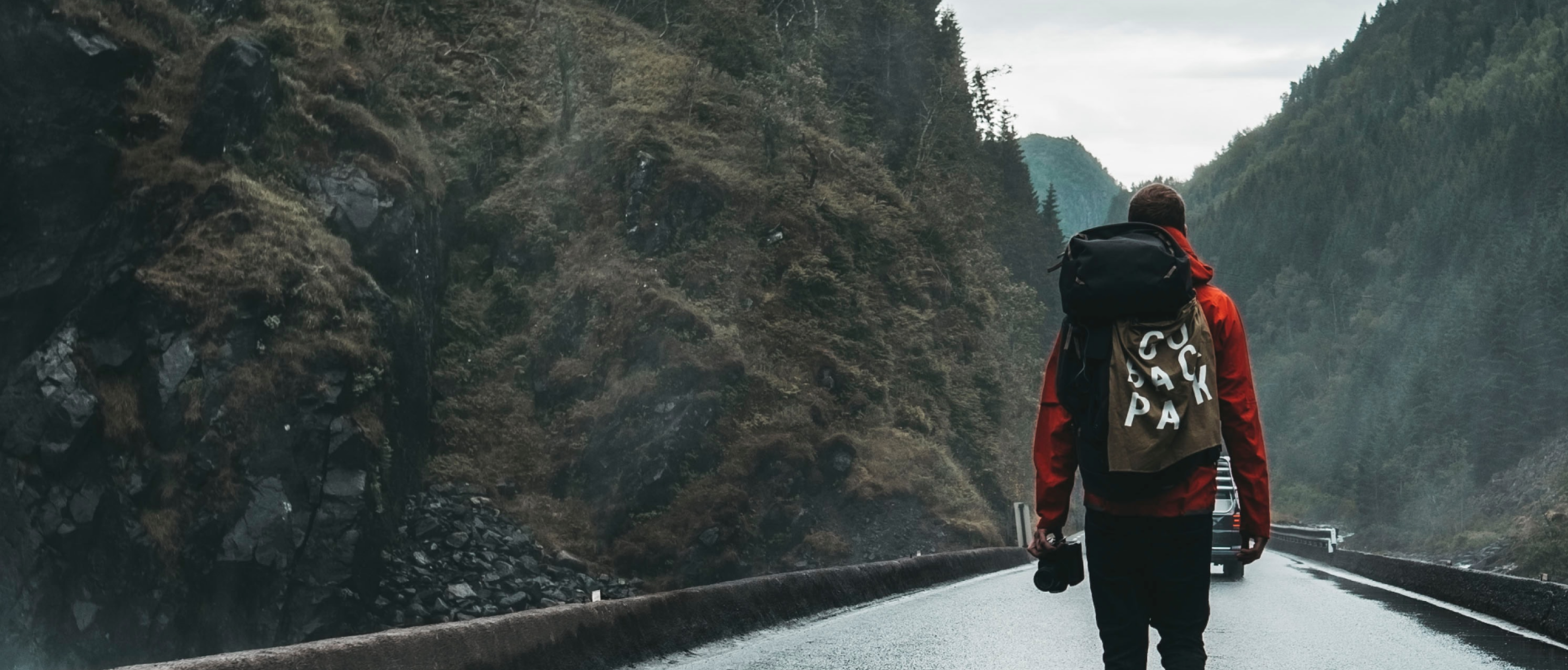Walker taking a trip outdoors on road in a narrow valley with rocks and forests